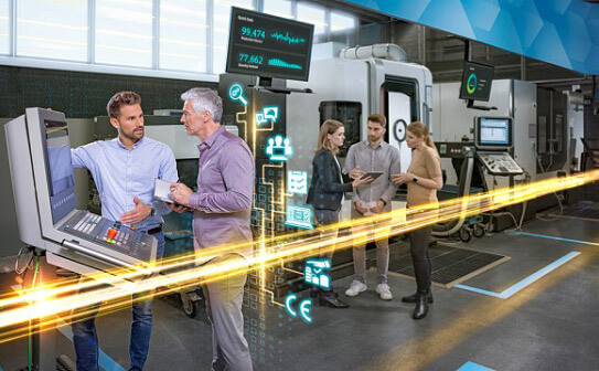 Bild von Siemens Mitarbeitern, die an einem Maschinenüberwachungsgerät stehen